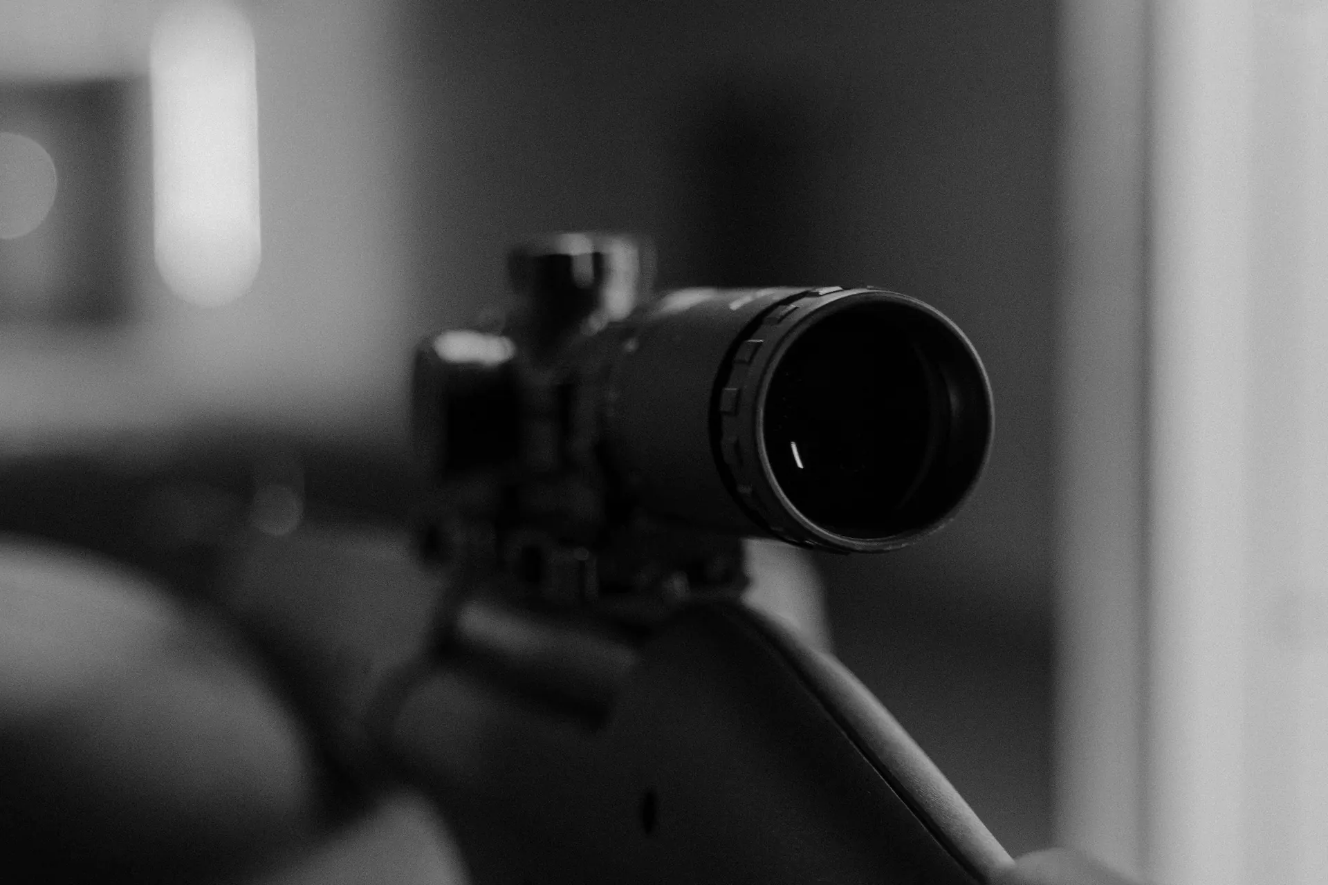 Carabine équipée d'une lunette posée au poste de tir, en noir et blanc