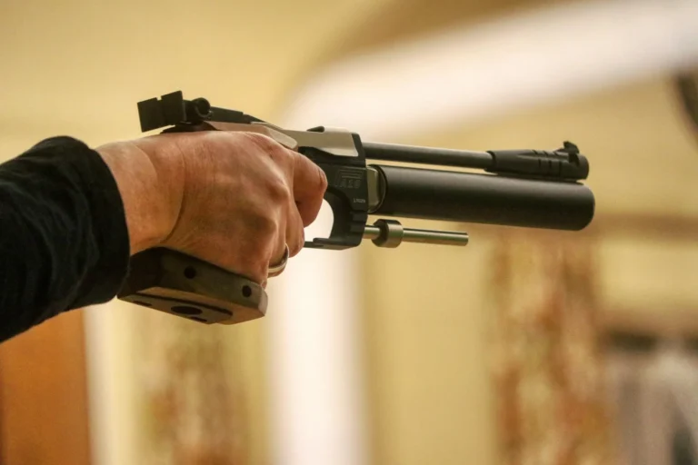 Tireur au pistolet à air comprimé 10 mètres, bras tendu vers la cible