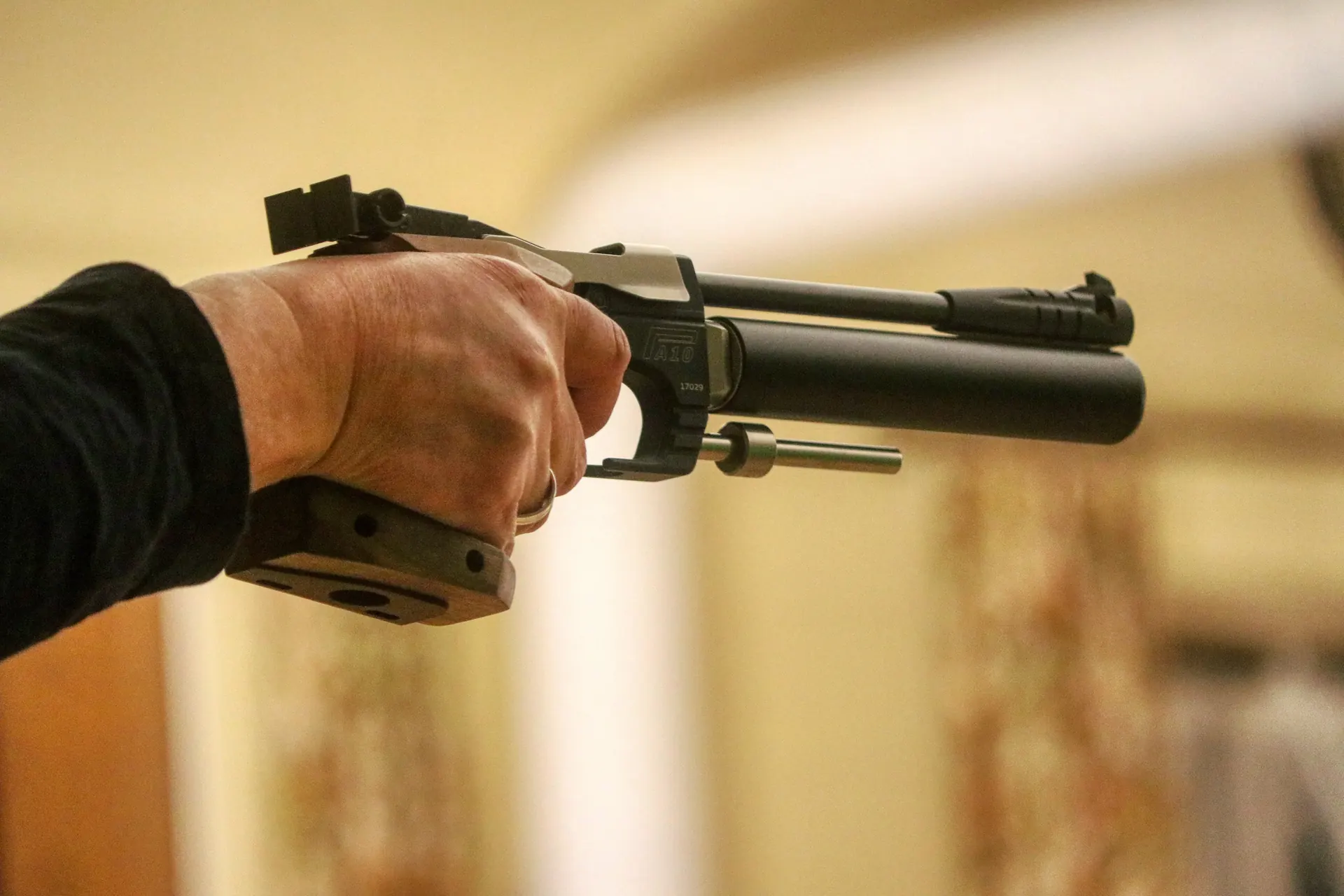 Tireur au pistolet à air comprimé 10 mètres, bras tendu vers la cible