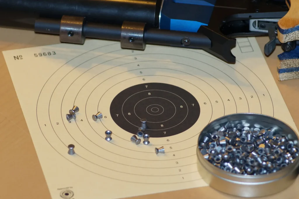 Pistolet à air comprimé, carton de cible 10 mètres et boîte de plombs sur une table de tir